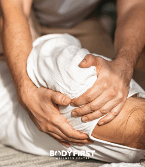 shoulder massage | Body First Wellness Center hand on shoulder